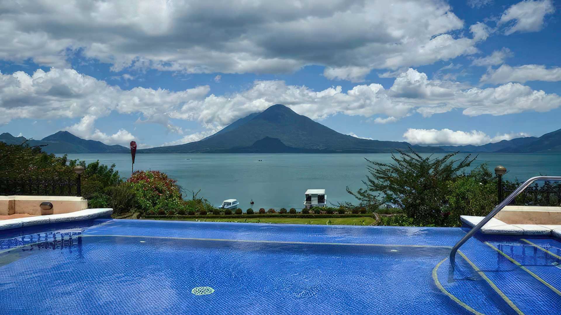 The breathtaking view of Lake Atitlan's serene waters and surrounding landscape is captured from the vantage point of the hotel's inviting swimming pool.
