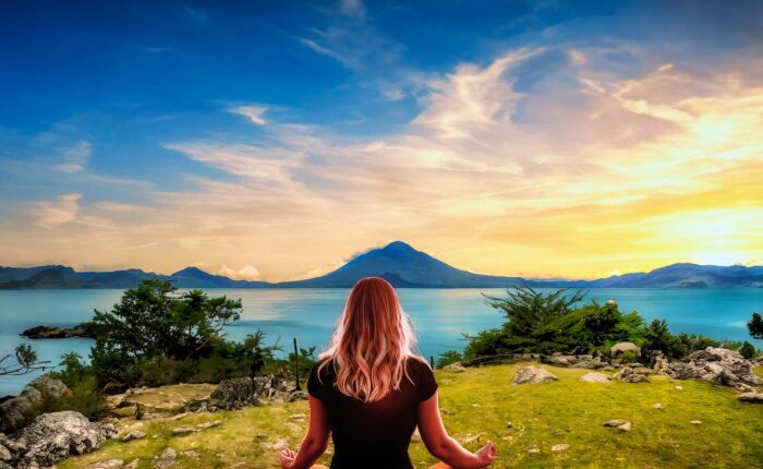 Woman meditating in a serene session at Lake Atitlan, surrounded by natural beauty, as part of the Guatemala Nature and Wellness Expedition