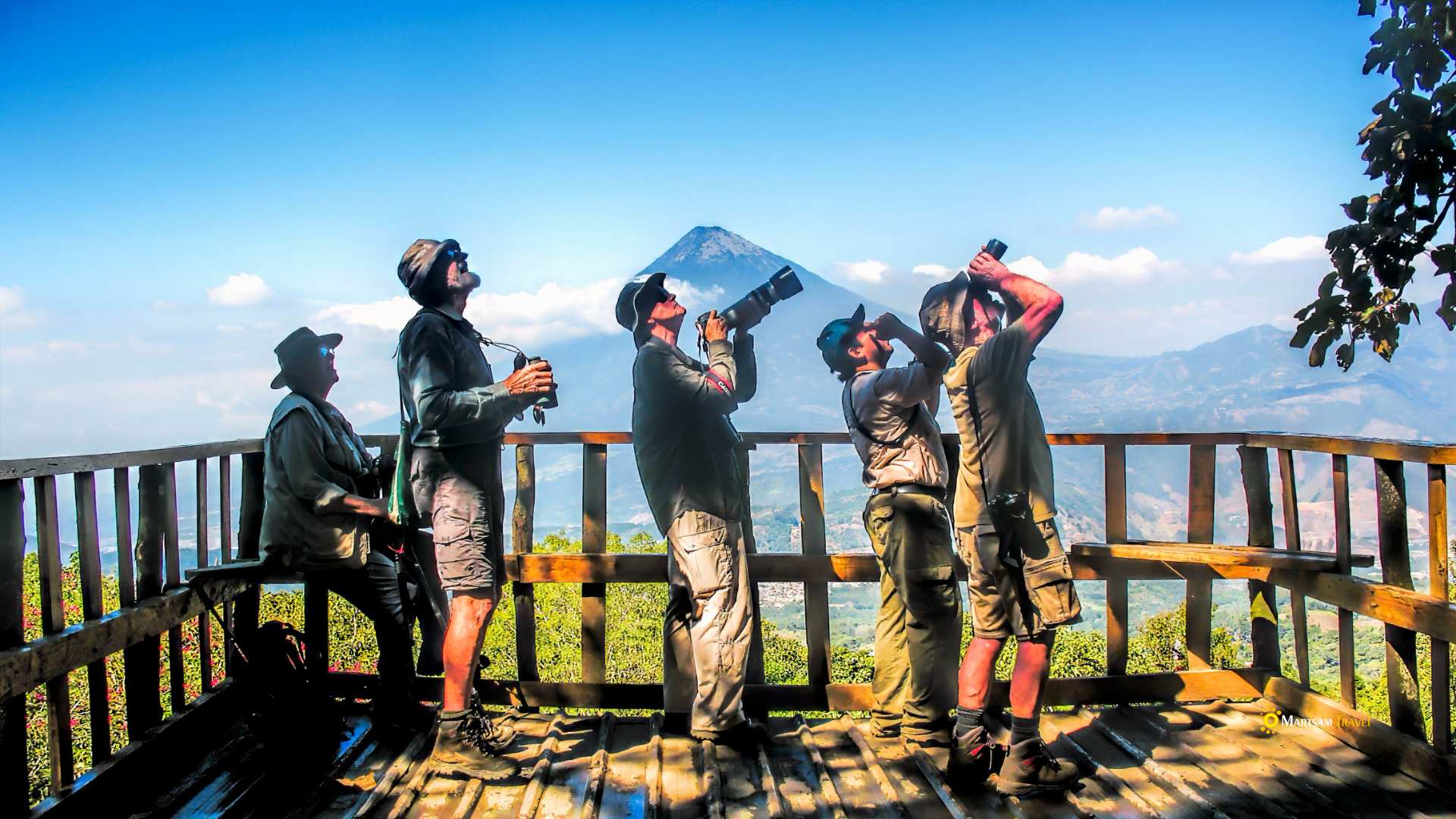 Group of birdwatchers observing avian species atop El Pilar Farm, surrounded by the lush landscapes of Antigua, Guatemala.