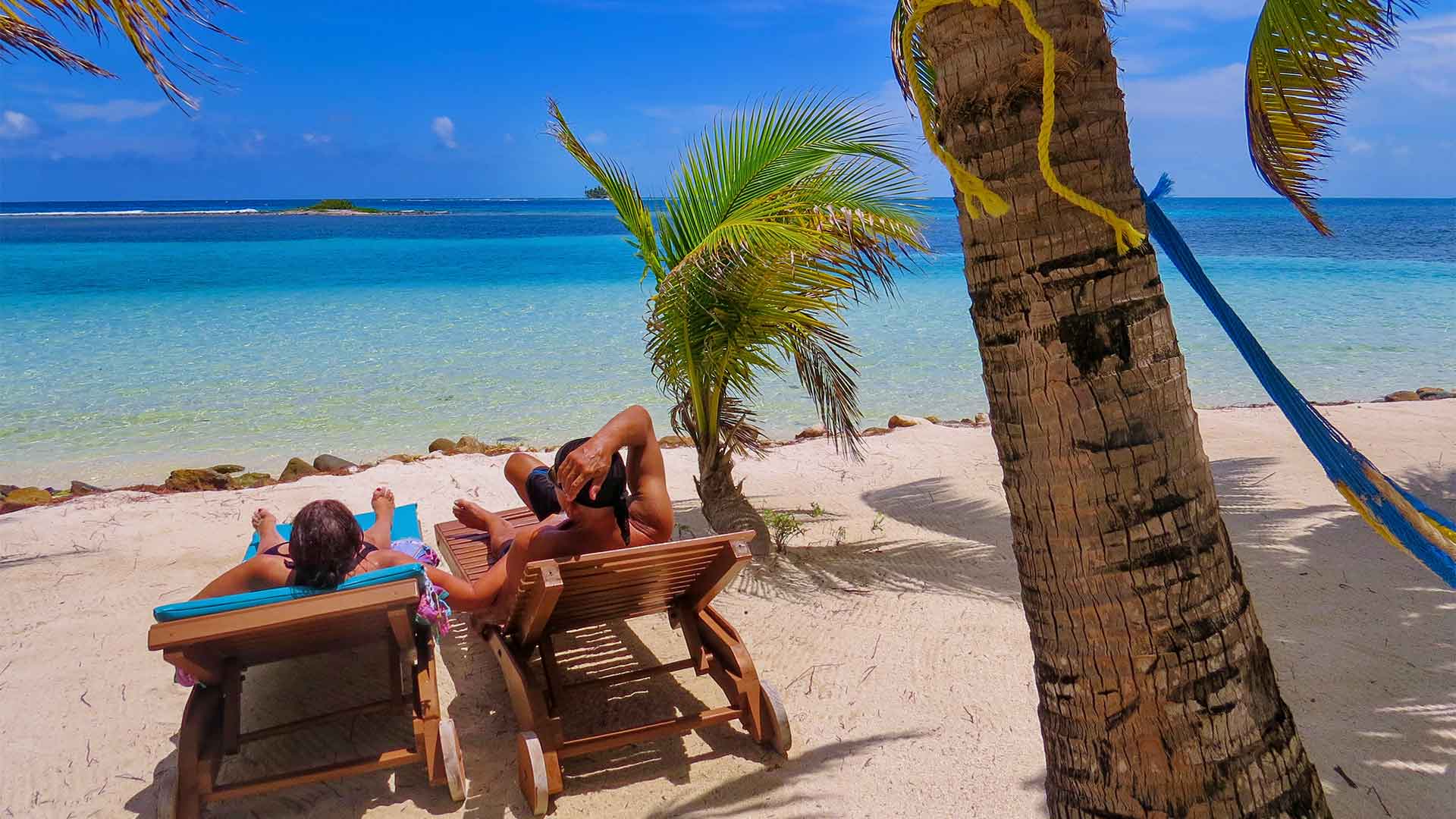 A happy couple leisurely relaxing on Belize's pristine white sand beaches, enjoying the tranquil azure waters and serene coastal ambiance.
