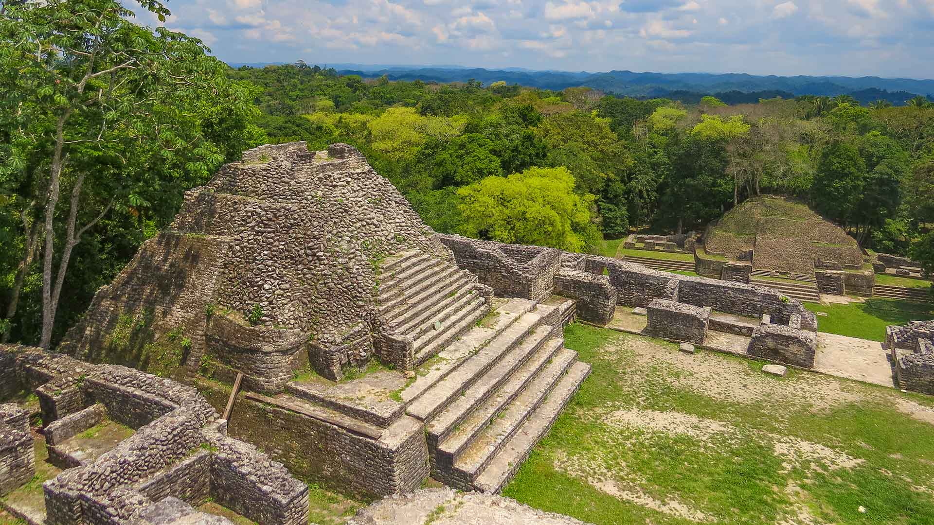 Panoramic view from atop the Caana Pyramid at Caracol Maya Ruins, showcasing the ancient structures and lush Belizean jungle below.