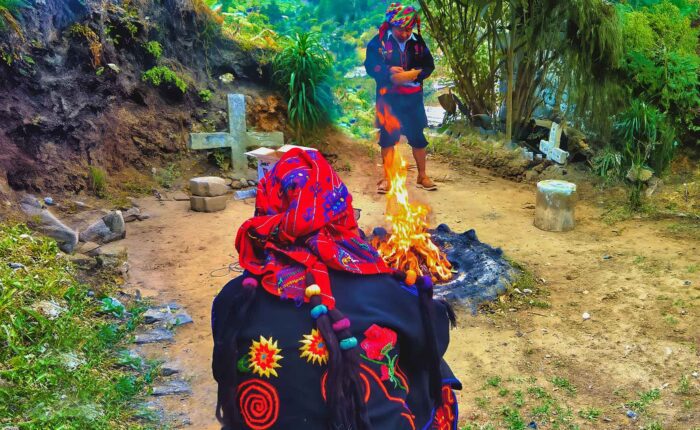 Guatemala Maya Shamanic Ceremonies: "Two Maya priests engaged in a Guatemala Maya Shamanic Ceremony at a sacred shrine, seated opposite each other with a firelight altar between them, wearing vibrant ceremonial attire."