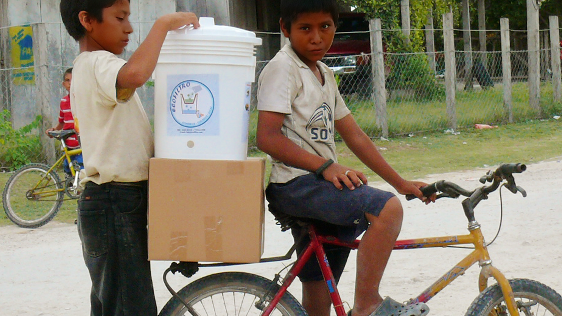 Two young men transport the Ecolfilter on their bicycle as part of the Pure Water Pathways Program, a sustainable initiative by Martsam Travel.