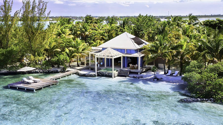 Casa Olita at Cayo Espanto, Belize – a charming wooden cabana among coconut trees with a private beach deck and turquoise waters, perfect for luxury vacation packages in Belize.