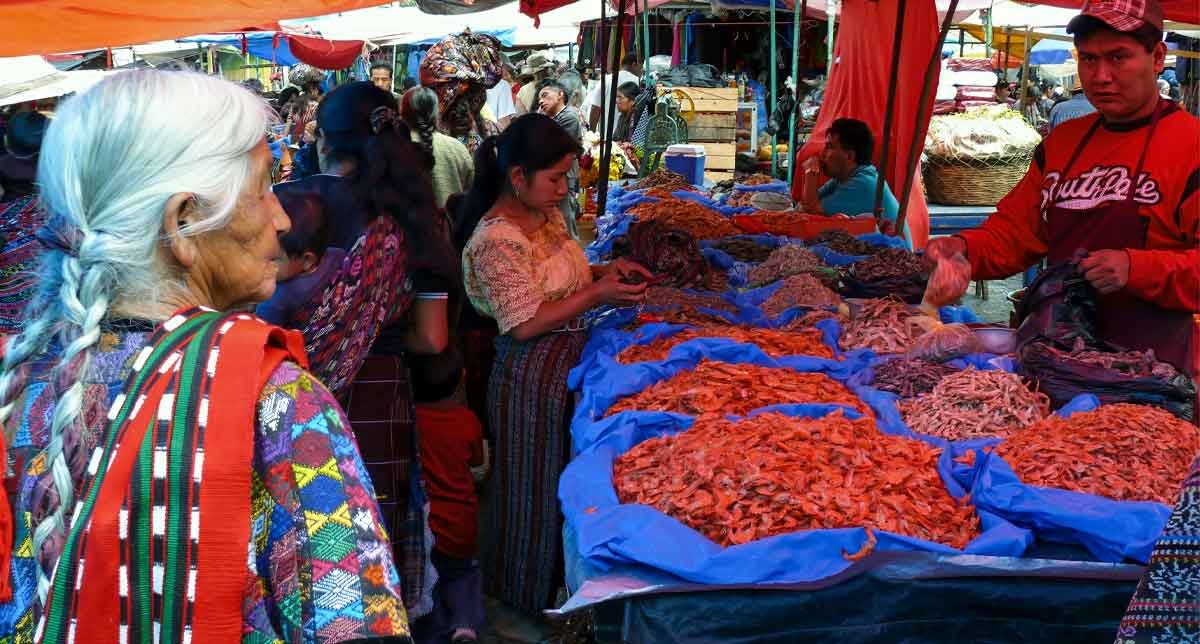 Colorful market scene at Lake Atitlán with locals selling handmade crafts, textiles, and fresh produce in a lively, cultural atmosphere.