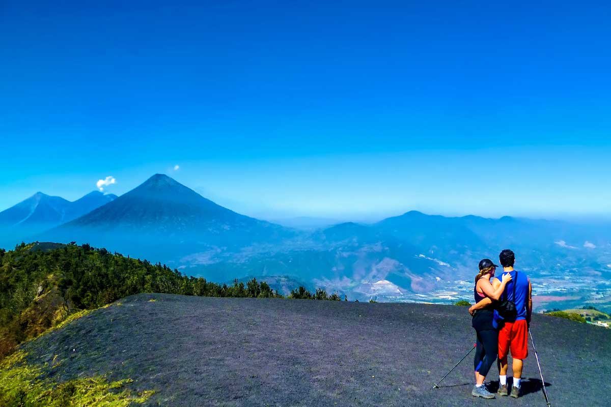 Couple enjoying panoramic views from the summit of Pacaya Volcano, overlooking Guatemala’s volcanic chain during one of our custom Central America tours.