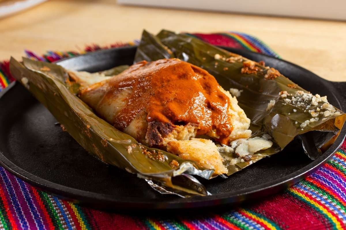 Traditional Guatemalan tamales wrapped in banana leaves, served with rice and salsa—an authentic example of Guatemalan cuisine.