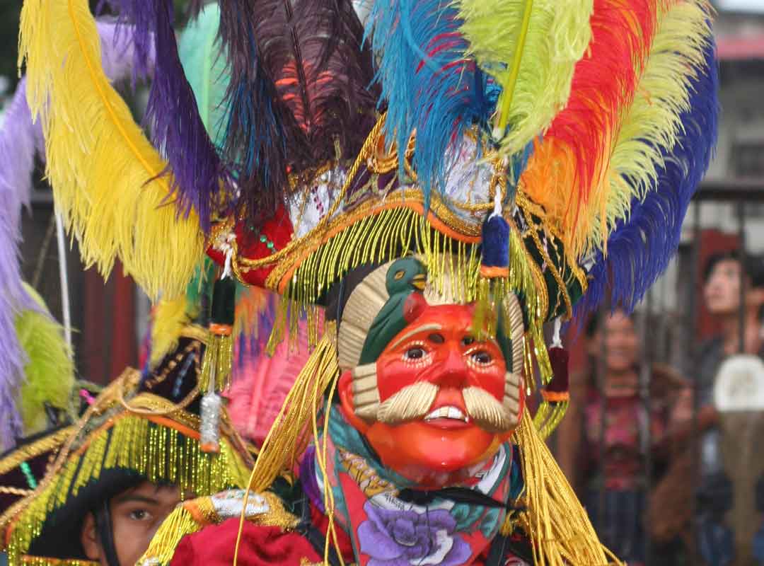 Mayan dancer at Chichicastenango Fair wearing colorful feathered headdress
