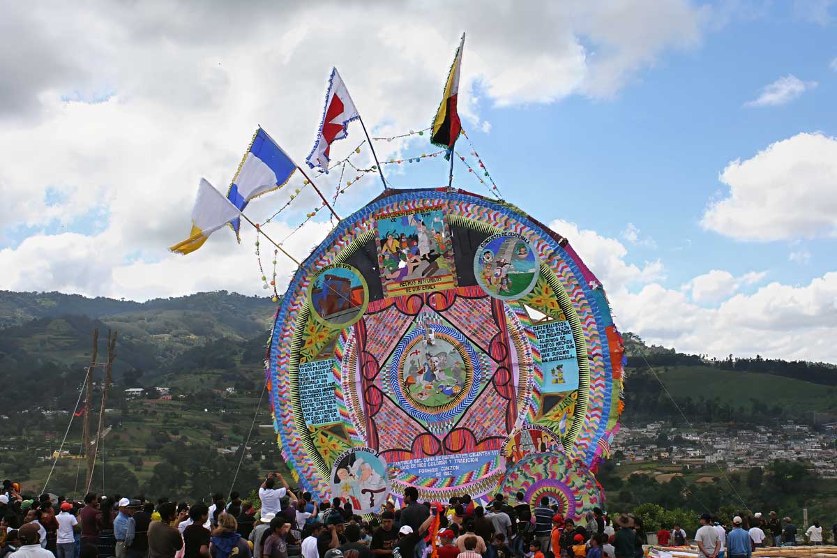 Colorful giant kite at the November festivals in the Mayan World, surrounded by crowds in Santiago Sacatepéquez, Guatemala.