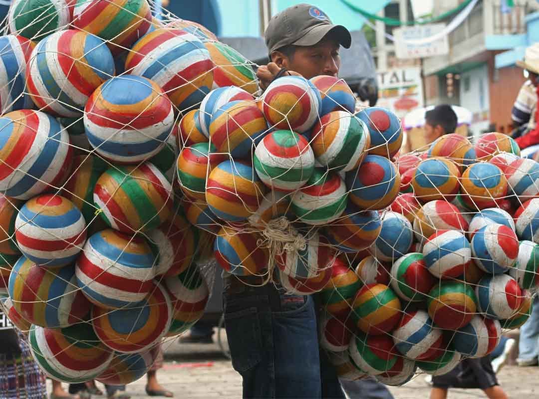 Vedndeordepelotas | martsam Young boy at the Chichicastenango Fair holding nets of colorful handmade balloons,
