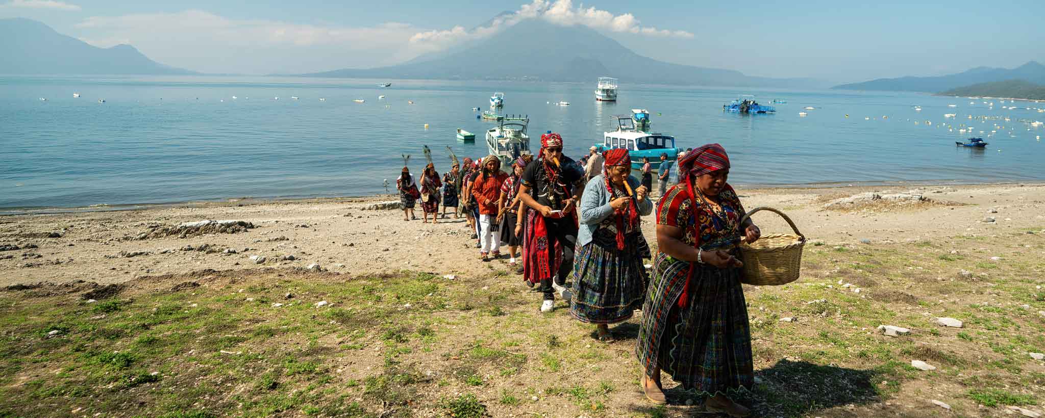 Maya spiritual guide leading a gratitude ceremony with community members beside Lake Atitlán and surrounding volcanoes during private cultural tours Guatemala experiences