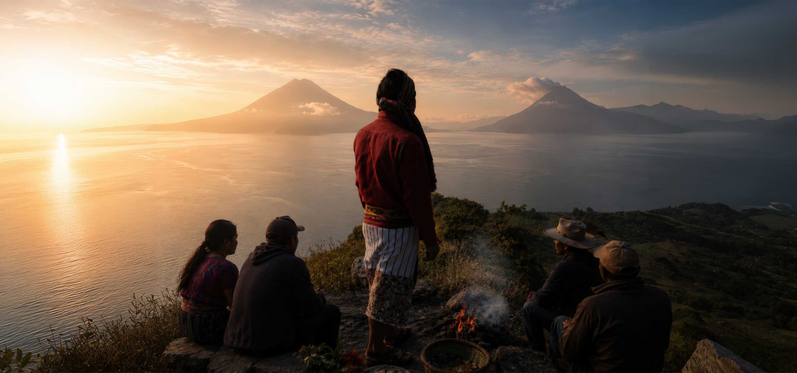Maya community gathered above Lake Atitlán at sunrise, overlooking the volcanoes while sharing stories and traditions rooted in Maya culture Guatemala