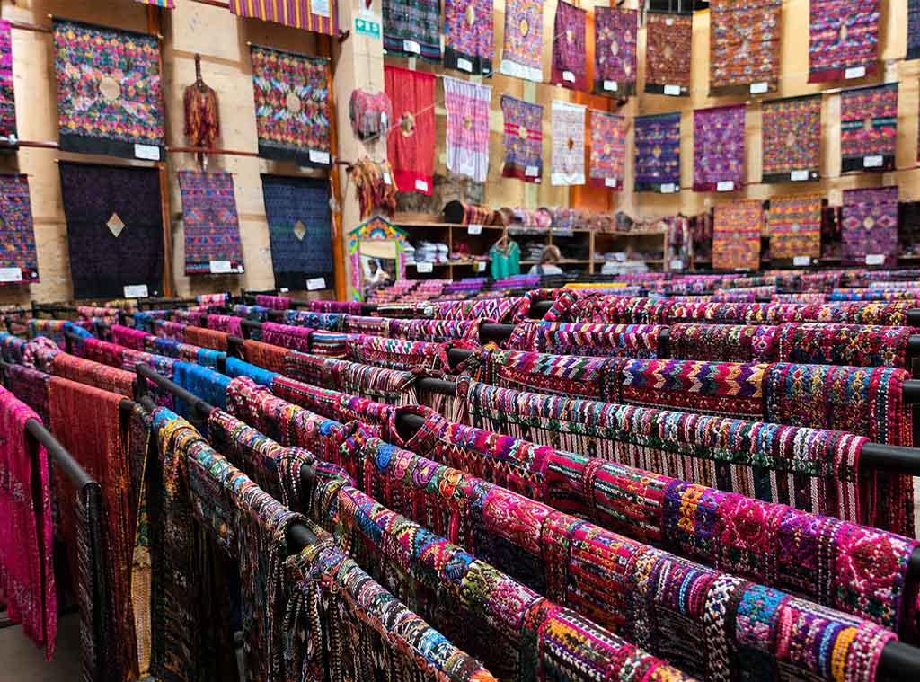 Colorful display of handwoven Maya textiles in a Guatemala artisan market, showcasing the craftsmanship, patterns, and traditions of traditional Maya clothing Guatemala.