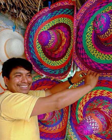 Artisan arranging colorful woven hats at a Yucatán market featured in Martsam’s Mexico tour packages.