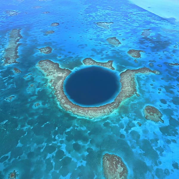 Blue-hole-belize | martsam travel Blue Hole: Aerial view of Belize’s Great Blue Hole and surrounding coral reef, featured in Vacation Packages for Belize.