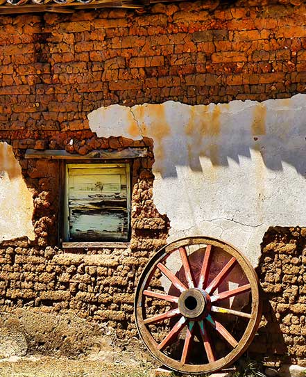 El-salvador-classic-tour | martsam travel Traditional adobe wall and wooden wagon wheel representing rural heritage on the El Salvador Classic Tour.