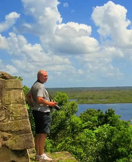 Lamanai-temple-lagoon-view | martsam travel Traveler standing on a Maya temple at Lamanai with the lagoon and tropical forest below.