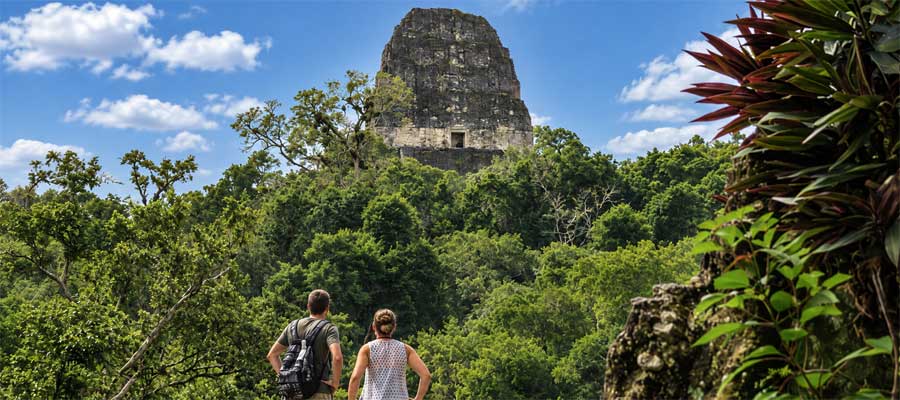 Travelers overlooking a Maya temple in Tikal’s rainforest during luxury Central America tours.