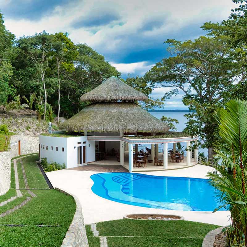Lakeside hotel with a swimming pool and thatched roof, featured among places to stay on custom Central America tours.